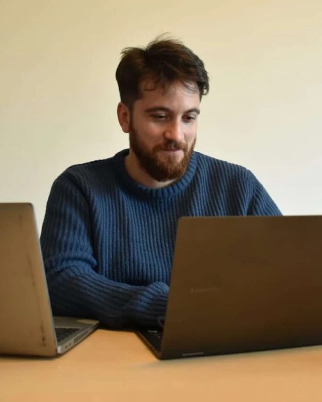 Stefano Antonucci al lavoro alla scrivania con due portatili